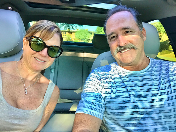 Smiling couple sitting in car before going on road trip