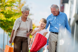 Grandparents with grandchild smiling with red shopping bag