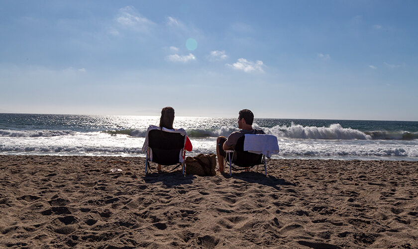 Couple staying at Channel Island Shores enjoy the beach sitting in beach chairs