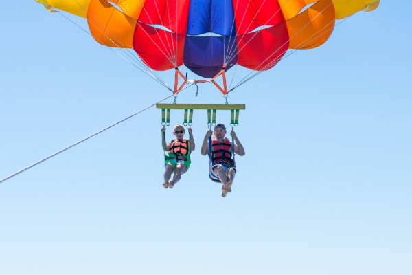 couple parasailing up in the sky with parachute behind them
